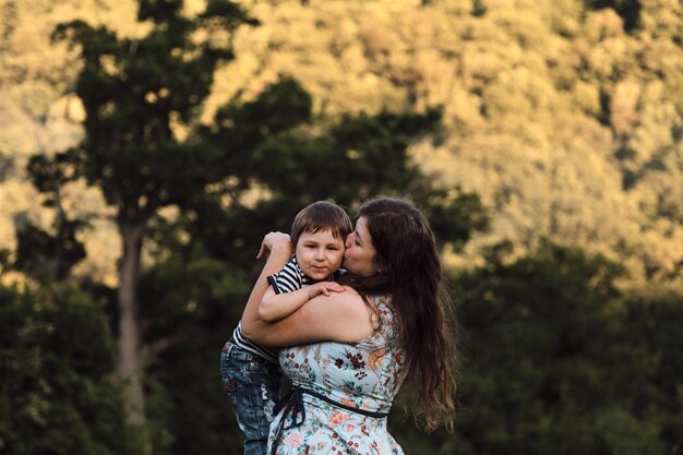 Mãe abraça seu filho pequeno e lhe dá um grande beijo amoroso na bochecha