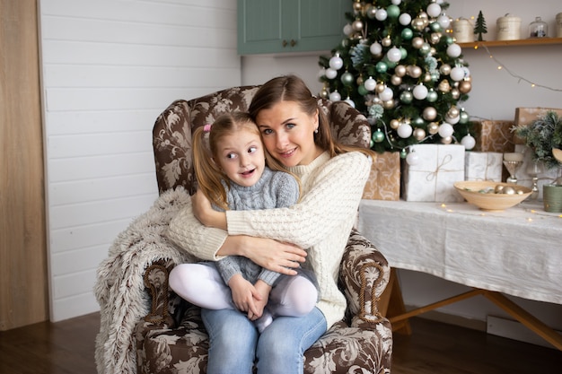 Mãe, abraçando a filha no fundo de casa de Natal