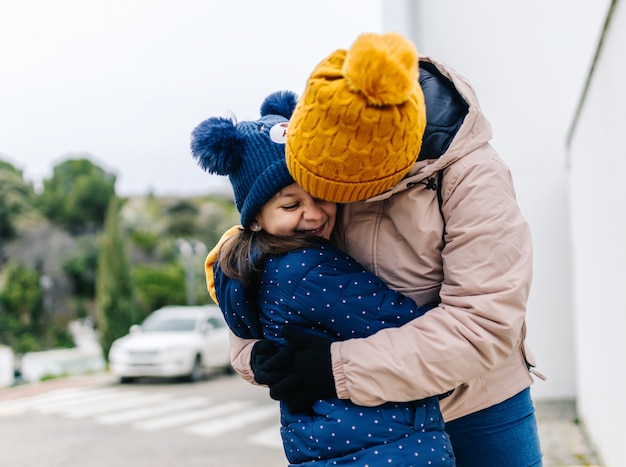 Foto mãe abraçando amorosamente sua filha sorridente na rua