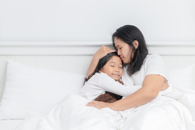 Mãe abraçando e beijar a filha na cama