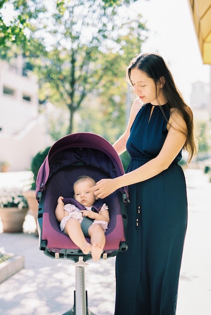 Mãe acariciando um bebê em um carrinho na rua