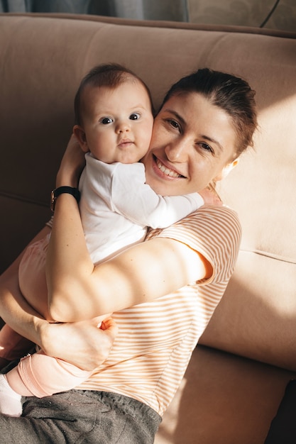 Mãe adorável com sardas abraçando a filha sorrindo para a câmera