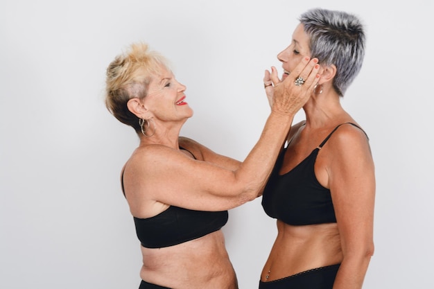 mãe adulta madura posando dando amor à sua filha em roupa interior estúdio tirou fundo branco