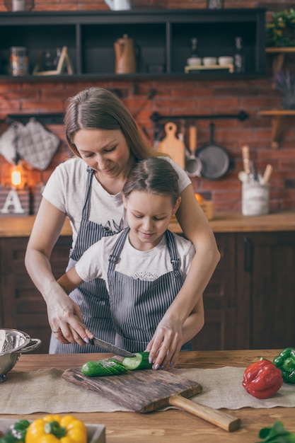 Mãe ajudando a filha a cozinhar