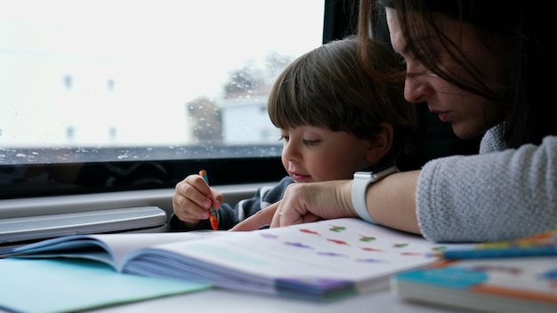 Mãe ajudando criança a fazer sua lição de casa enquanto viaja em trem de alta velocidade Pai ensinando menino