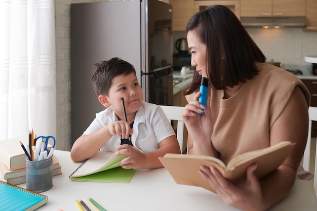 Mãe ajudando o filho a fazer lição de casa para a escola e explicando o tópico