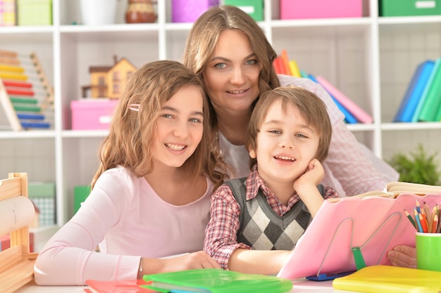 Mãe ajudando o filho pequeno e a filha adolescente com o dever de casa