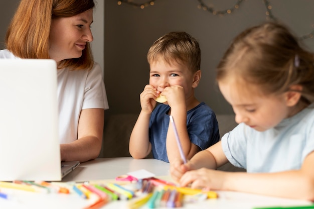 Foto mãe ajudando seus filhos a fazerem a lição de casa