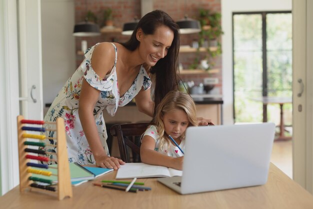 Mãe ajudando sua filha com os trabalhos de casa em uma casa confortável