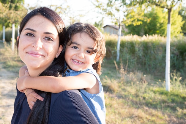 Foto mãe alegre muito nas costas com filha linda menina