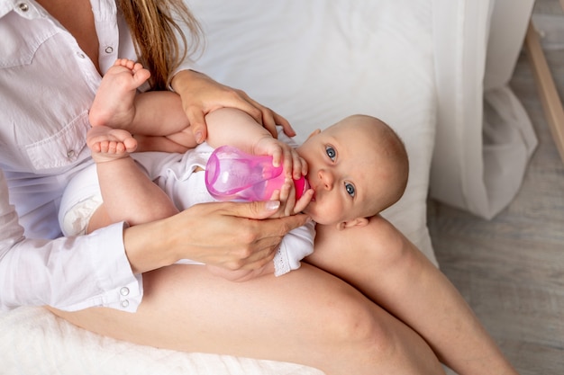 Mãe alimenta bebê com leite de mamadeira