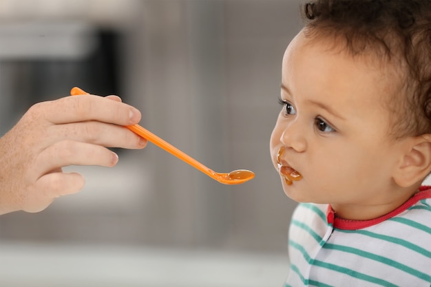 Mãe alimentando bebê com colher dentro de casa