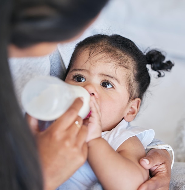 Mãe alimentando bebê com fórmula e mamadeira com nutrição e família saudável e crescimento com desenvolvimento na primeira infância A criança está bebendo refeição e as pessoas em casa com saúde e bem-estar