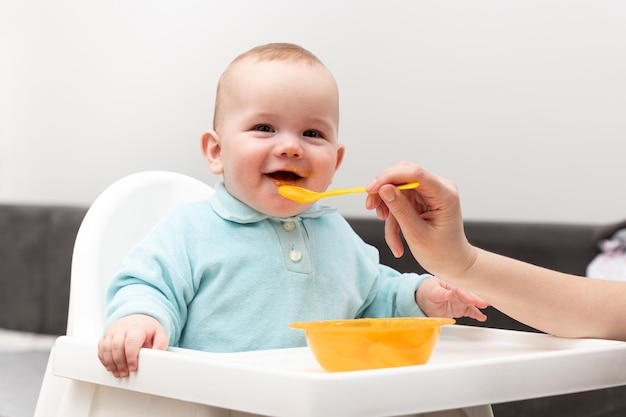 Mãe alimentando bebê sentado na cadeira