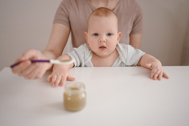 Mãe alimentando purê para um recém-nascido.