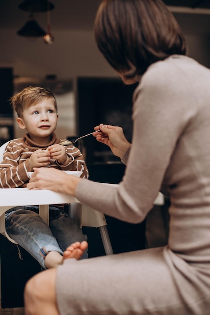 Mãe alimentando seu filho bebê sentado na cadeira