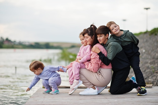 Mãe ama mãe com quatro filhos ao ar livre no píer Grande família esportiva passa tempo livre ao ar livre