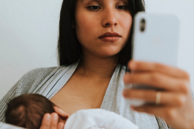 Mãe amamentando usando um smartphone