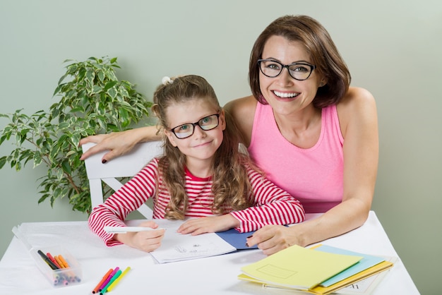 Mãe amorosa, ajudando a filha a escrever no caderno