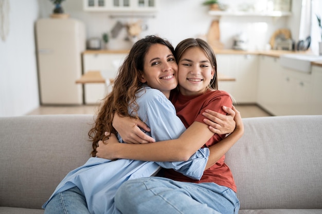 Mãe amorosa jovem abraçando abraçando sua filha adotiva feliz em casa expressando amor