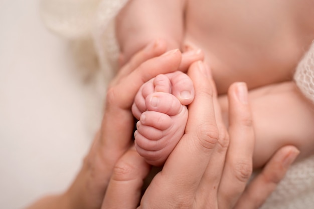 Mãe amorosa segura as pernas do bebê. Infância feliz. Cuidado paterno. Conceito de família feliz.