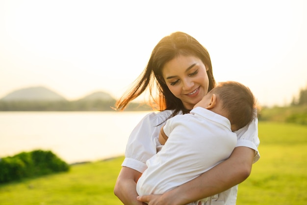 Mãe amorosa segurando e carregando seu bebê recém-nascido no parque público