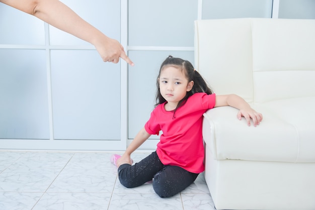 Mãe apontando o dedo para a filha enquanto repreende a filha em casa