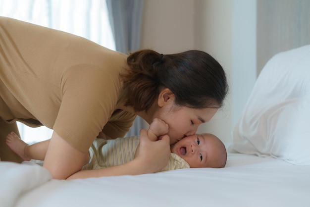 Mãe asiática brincando com seu bebê recém-nascido no quarto em casa para promover as relações familiares e o bom desenvolvimento do bebê