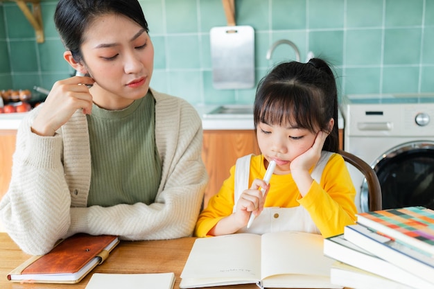 Mãe asiática e filha estudando juntas em casa