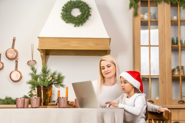 Mãe asiática e filha usando laptop Vídeo chamada Facetime conversando comunicação com o pai com decoração de árvore de Natal em um quarto branco em casa. Rosto sorridente e feliz por celebrar o festivel de ano novo.