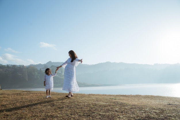 Mãe asiática grávida de filha se divertindo ao nascer do sol