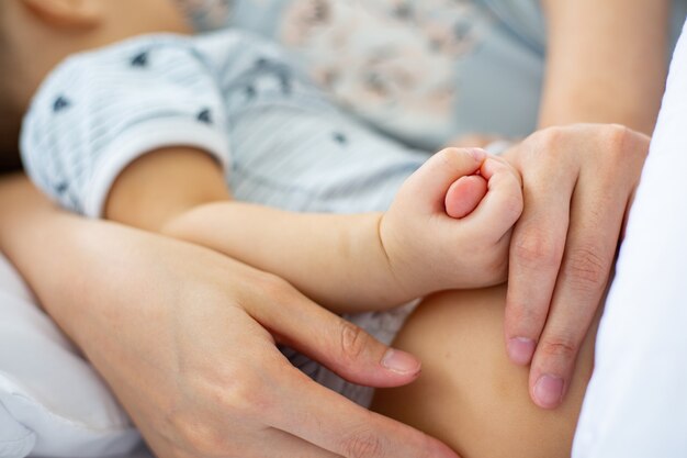 Mãe asiática segurando seu bebê ao lado do quarto.