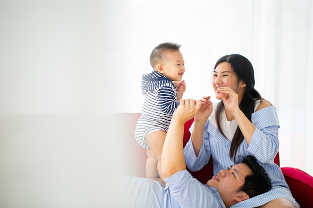 Mãe asiática segurando seu bebê ao lado do quarto.