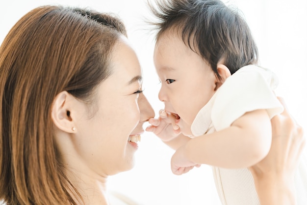 Mãe asiática segurando um bebê na sala iluminada