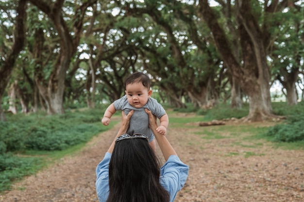 Mãe asiática, segurando um bebê no parque