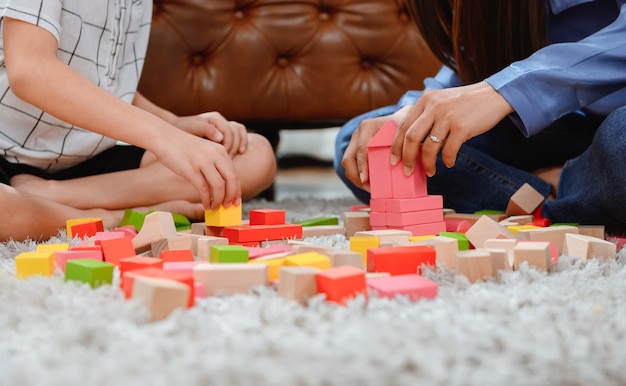 Mãe asiática trabalha em casa junto com o filho. Mãe e filho jogam bloco de madeira de cor. Criança criando brinquedo de construção. Estilo de vida da mulher e atividade familiar.