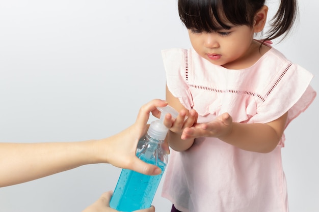 Mãe asiática usando gel anti-séptico de álcool para limpar as mãos do bebê. Desinfecção por coronavírus