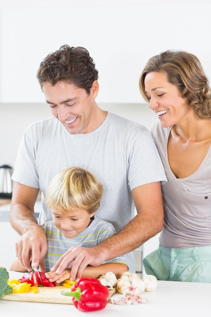 Mãe assistindo como filho e marido preparam legumes