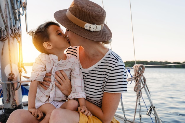 Mãe atraente com seu adorável filho pequeno navegando no mar em veleiro