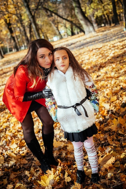 Mãe atraente e sua filhinha feliz caminhando juntas no parque outono