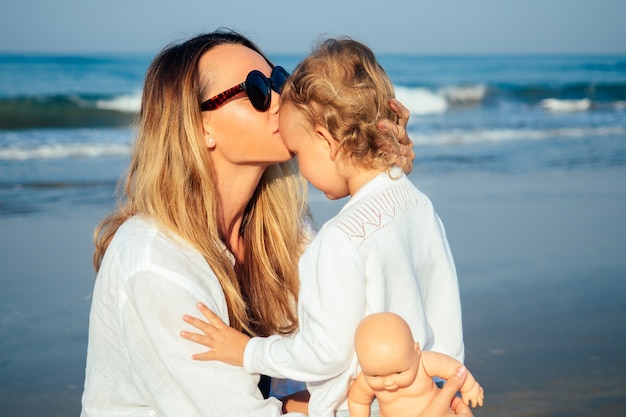 Mãe beija a filha de manhã na praia