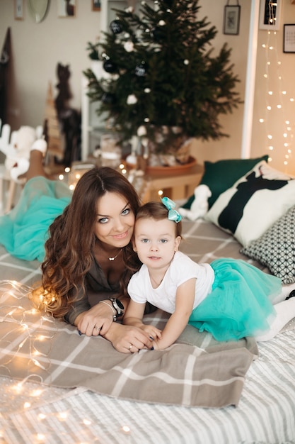 Mãe beijando a filha, deitada na cama