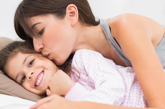 Mãe beijando filha feliz na bochecha