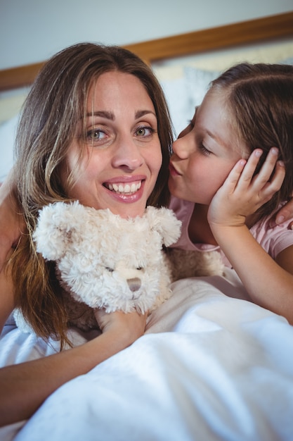 Mãe beijando filha na cama