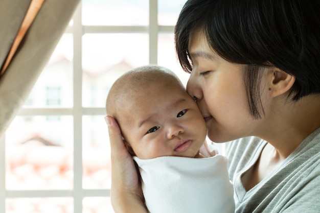 Mãe beijando o bebê em casa