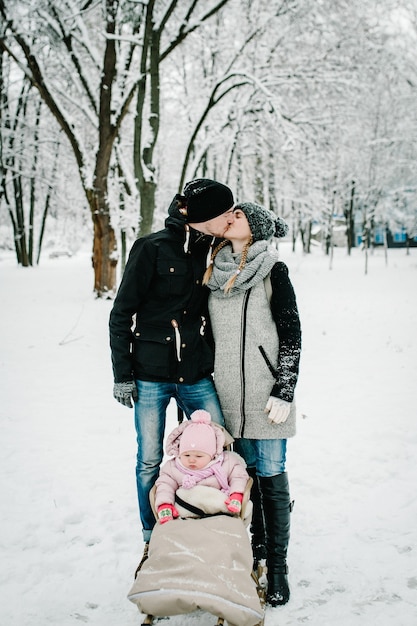 Mãe beijando pai e filha ficar ao ar livre no inverno de fundo.