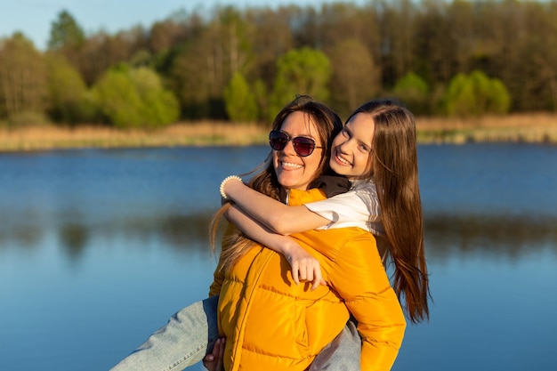 Mãe brincalhona dando carona à filha na margem do lago primavera