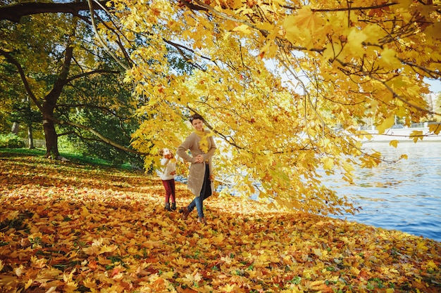 Mãe, brincando com a filha no parque. Mãe e filha brincando juntos no outono a pé ao ar livre. Família amorosa feliz se divertindo. mãe elegante e desgaste infantil.