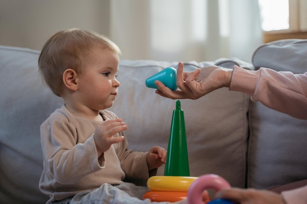 Mãe brincando com bebê fofo jogo de pirâmide infantil dando brinquedo sentado em casa Desenvolvimento infantil