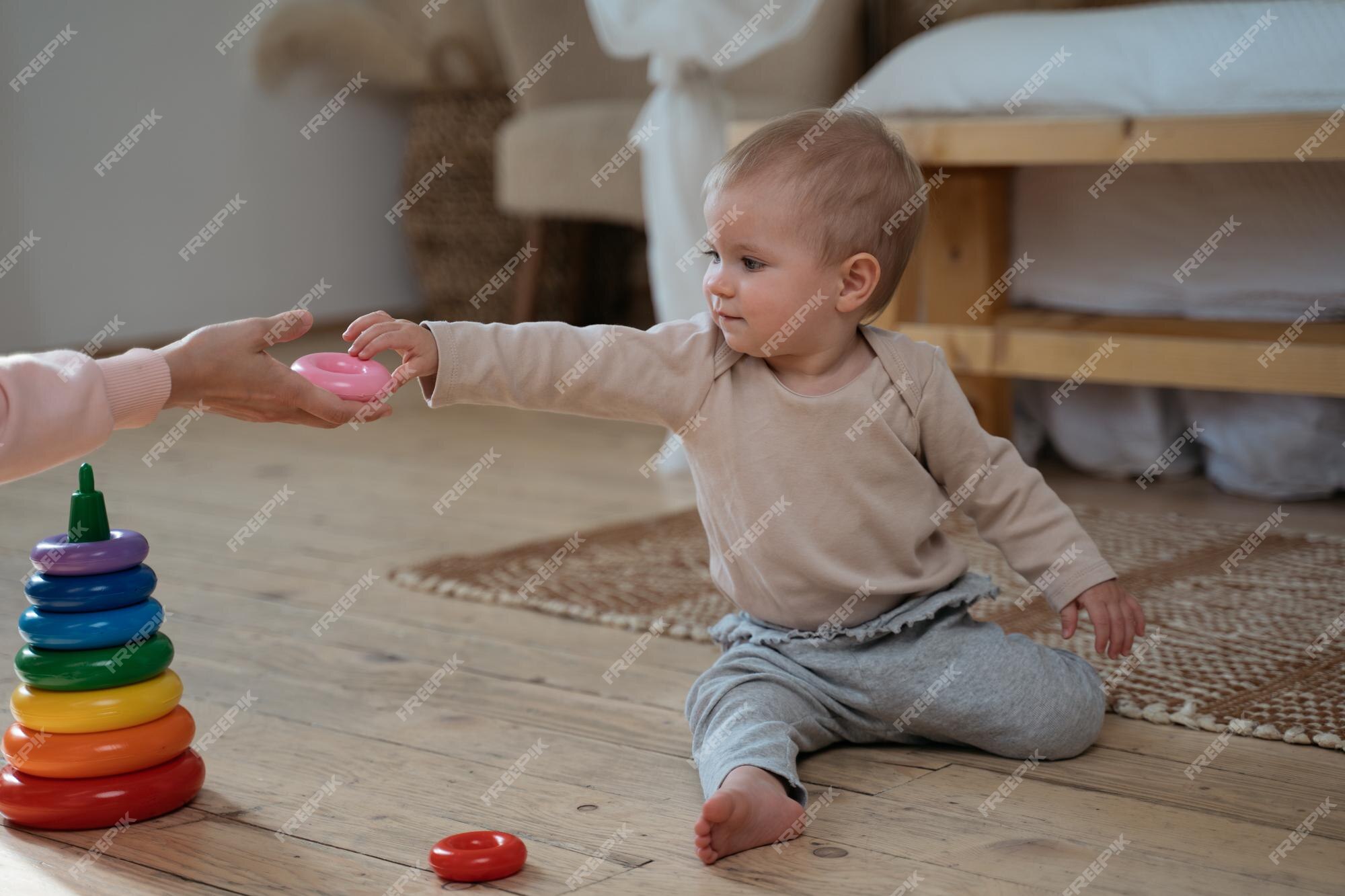 Mãe brincando com o jogo de pirâmide de bebê de 1 ano sentado em casa